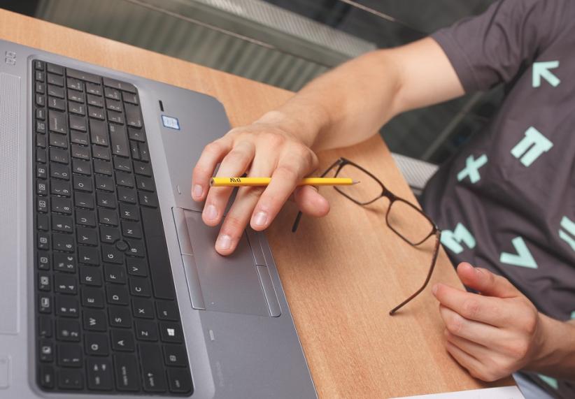 Photo shows a hand writing on the keyboard.